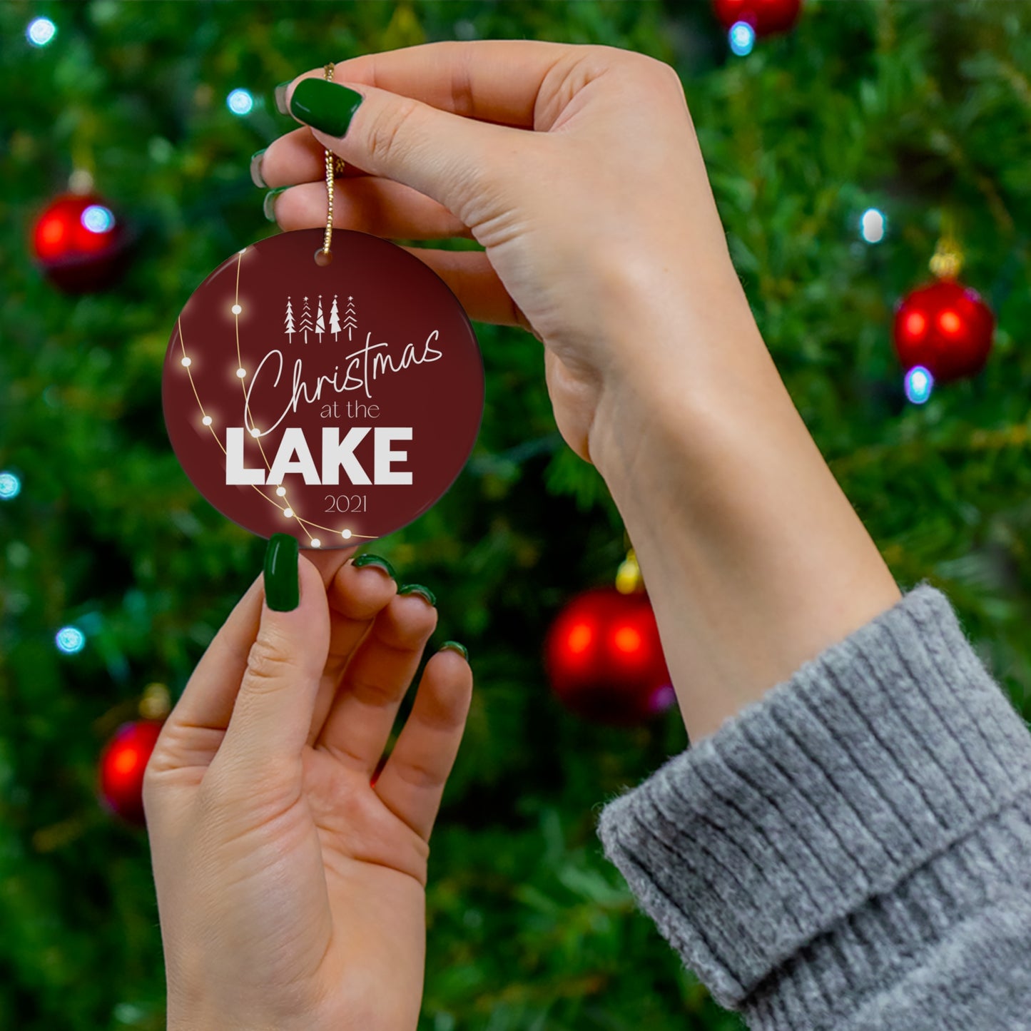 Christmas at the Lake 2021 Sparkling Lights Ceramic Ornament, elegant circle shaped tree ornament with a deep red colored background and white lettering